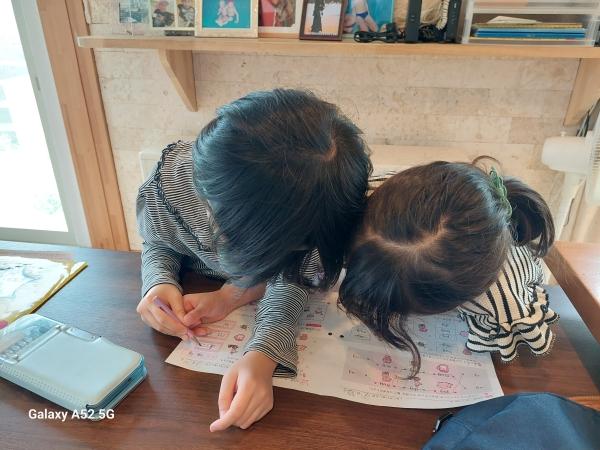 ht060137 小文字の”g”をうまく書けないでいた1年生の手を取り、一緒に書いてくれている2年生。